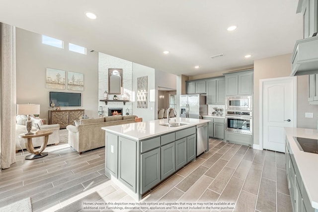 1107 Peacock Ln, Wylie, TX 75098 - kitchen with stainless steel appliances, a sink, a large fireplace, light countertops, and recessed lighting