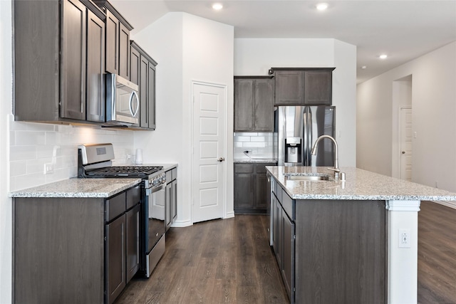 855 Revere Ct, Fate, TX 75189 - kitchen featuring appliances with stainless steel finishes, dark wood-type flooring, a sink, a kitchen island with sink, and tasteful backsplash