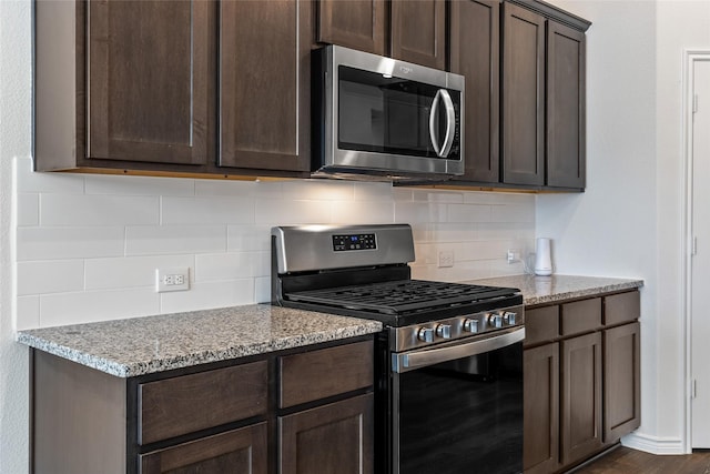 855 Revere Ct, Fate, TX 75189 - kitchen featuring appliances with stainless steel finishes, dark brown cabinets, decorative backsplash, light stone counters, and dark wood finished floors