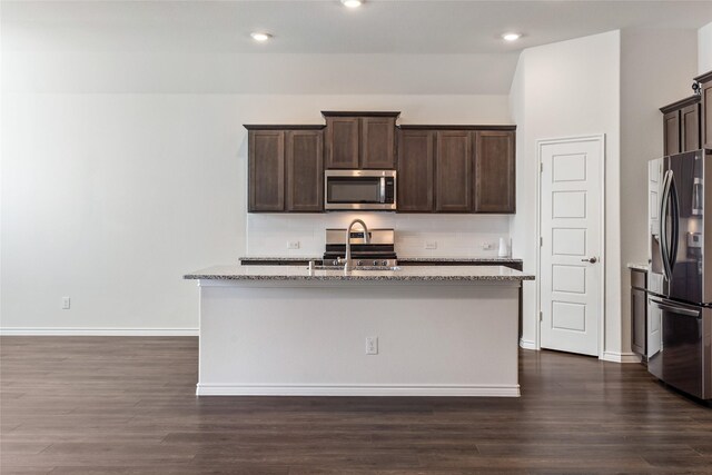 855 Revere Ct, Fate, TX 75189 - kitchen with appliances with stainless steel finishes, dark brown cabinetry, a center island with sink, dark wood-style flooring, and recessed lighting