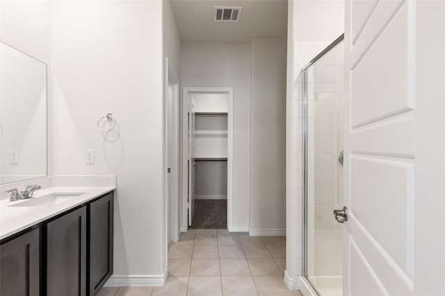 855 Revere Ct, Fate, TX 75189 - bathroom with vanity, a shower stall, a walk in closet, tile patterned flooring, and baseboards