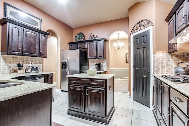 2318 Sparrow Dr, Forney, TX 75126 - kitchen featuring appliances with stainless steel finishes, arched walkways, dark brown cabinets, decorative backsplash, and light tile patterned flooring