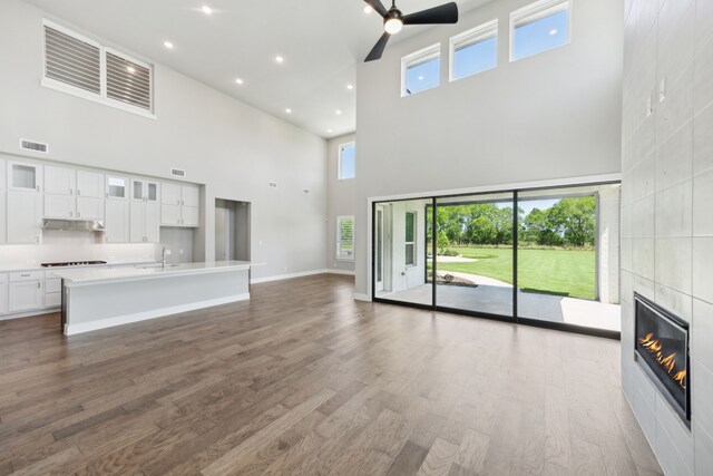 4106 Tamarack Ln, Royse City, TX 75189 - unfurnished living room featuring a high ceiling, a sink, ceiling fan, a tile fireplace, and wood finished floors