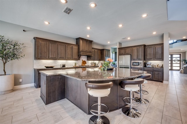 433 Silver Chase Dr, Keller, TX 76248 - kitchen with fridge, stainless steel microwave, tasteful backsplash, a spacious island, and dark stone countertops