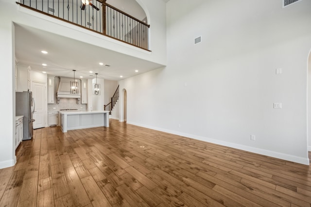 5901 Kildare Ct, Mckinney, TX 75071 - unfurnished living room featuring arched walkways, light wood-style floors, baseboards, recessed lighting, and a towering ceiling