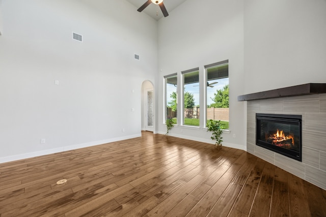 5901 Kildare Ct, Mckinney, TX 75071 - unfurnished living room with a ceiling fan, a tile fireplace, wood finished floors, arched walkways, and baseboards