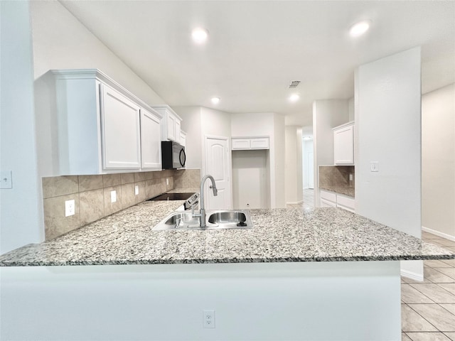 6940 Freeboard Way, Fort Worth, TX 76179 - kitchen with black microwave, a sink, a peninsula, light stone counters, and recessed lighting