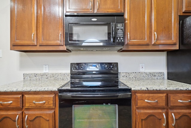 6132 Farrah Dr, Fort Worth, TX 76131 - kitchen featuring black appliances, brown cabinetry, and light stone counters