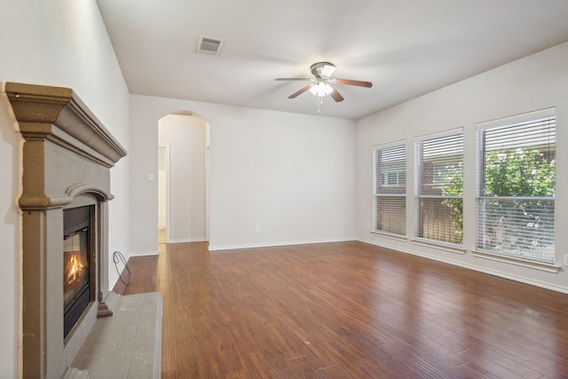 6132 Farrah Dr, Fort Worth, TX 76131 - unfurnished living room with ceiling fan, arched walkways, a fireplace with flush hearth, wood finished floors, and baseboards