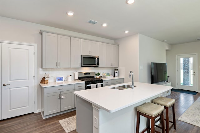 101 Goosewood Dr, Mckinney, TX 75071 - kitchen featuring stainless steel appliances, a sink, dark wood finished floors, gray cabinetry, and light countertops