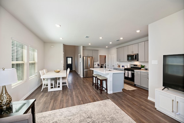101 Goosewood Dr, Mckinney, TX 75071 - kitchen featuring appliances with stainless steel finishes, a sink, gray cabinets, a kitchen bar, and dark wood finished floors