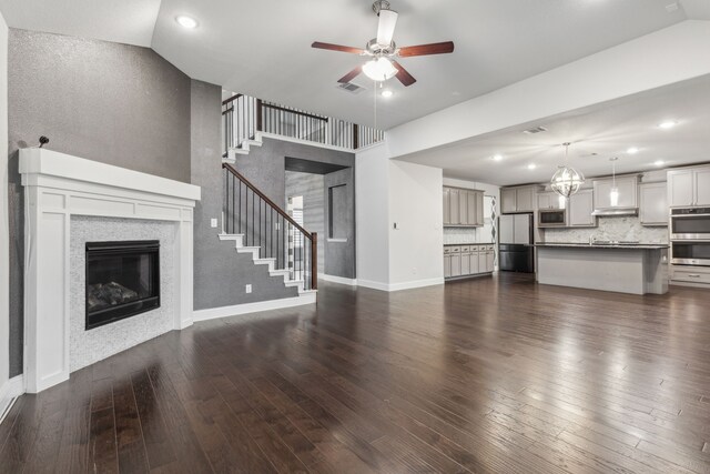 906 Overton Ave, Celina, TX 75009 - unfurnished living room with a glass covered fireplace, a ceiling fan, stairway, dark wood-type flooring, and baseboards