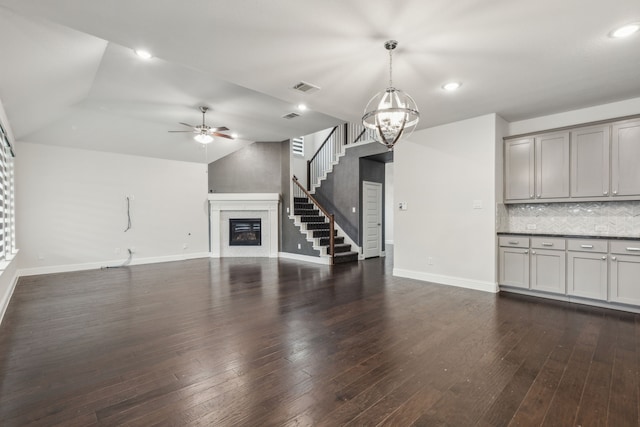 906 Overton Ave, Celina, TX 75009 - unfurnished living room with a glass covered fireplace, baseboards, a ceiling fan, a chandelier, and dark wood-style flooring