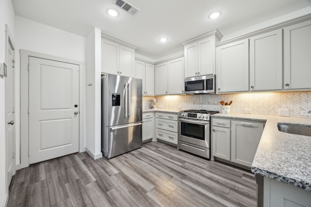 317 Mcconathy Way, Flower Mound, TX 75028 - kitchen featuring stainless steel appliances, recessed lighting, light wood-style flooring, backsplash, and light stone countertops