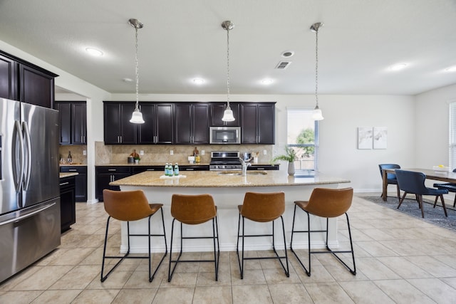 1901 Brahorn Ln, Fort Worth, TX 76131 - kitchen featuring appliances with stainless steel finishes, backsplash, a breakfast bar, a sink, and a kitchen island with sink