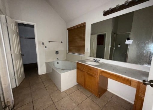 712 Mistymoor Ln, Fort Worth, TX 76052 - bathroom featuring lofted ceiling, a garden tub, a shower stall, vanity, and tile patterned flooring