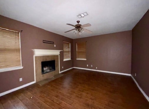 712 Mistymoor Ln, Fort Worth, TX 76052 - unfurnished living room with hardwood / wood-style floors, baseboards, a ceiling fan, and a tiled fireplace
