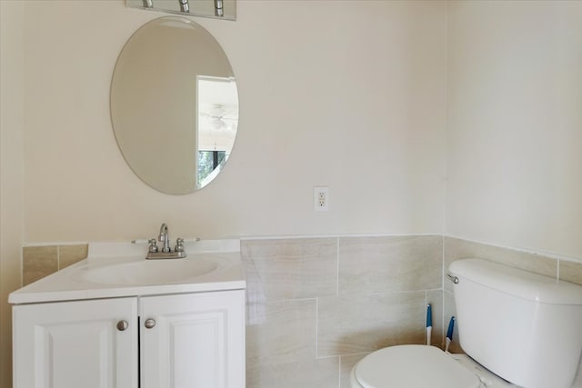 104 Mackinnon, Mount Pleasant, TX 75455 - bathroom with toilet, vanity, tile walls, and wainscoting
