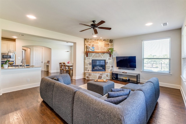 131 Lavaca Dr, Irving, TX 75039 - living area featuring arched walkways, ceiling fan, dark wood-style flooring, a stone fireplace, and recessed lighting