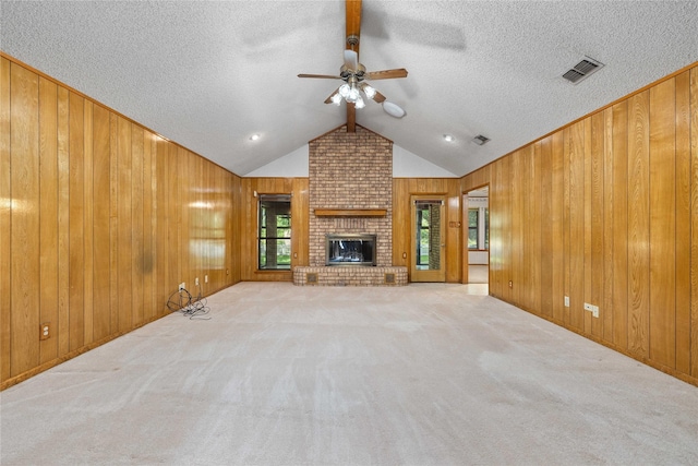 1025 S Lamar St, De Leon, TX 76444 - unfurnished living room with a ceiling fan, wooden walls, carpet floors, a textured ceiling, and a fireplace