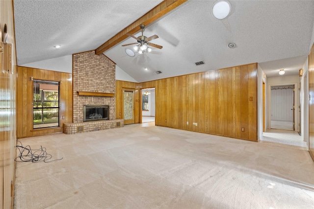 1025 S Lamar St, De Leon, TX 76444 - unfurnished living room with wooden walls, light colored carpet, ceiling fan, a textured ceiling, and a brick fireplace