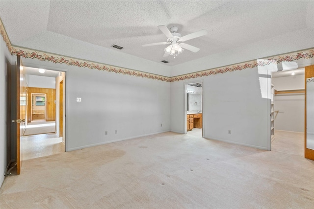 1025 S Lamar St, De Leon, TX 76444 - unfurnished bedroom with light colored carpet, a textured ceiling, a walk in closet, connected bathroom, and baseboards