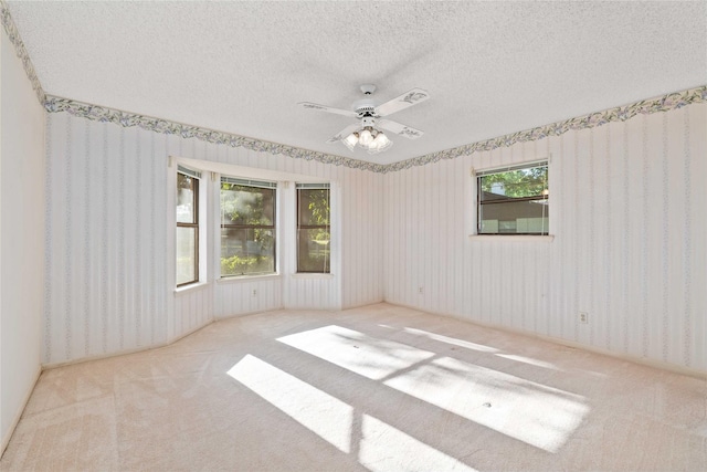 1025 S Lamar St, De Leon, TX 76444 - carpeted empty room with wallpapered walls, a ceiling fan, and a textured ceiling