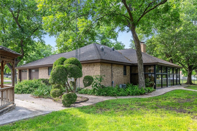 1025 S Lamar St, De Leon, TX 76444 - view of property exterior with brick siding, a chimney, a lawn, and a sunroom