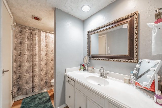 2216 Brigadoon Ct, Arlington, TX 76013 - full bath with vanity, toilet, a textured ceiling, a shower with curtain, and wood finished floors