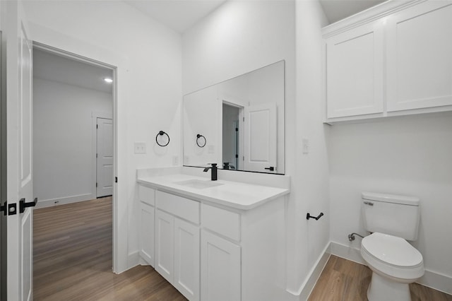 2738 W Washington St, Denison, TX 75020 - bathroom featuring wood finished floors, vanity, toilet, and baseboards