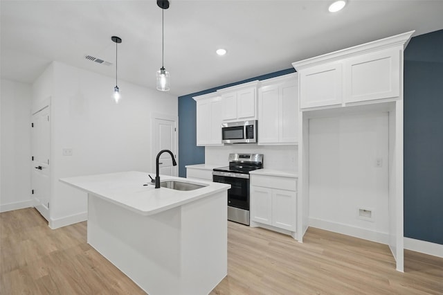 2738 W Washington St, Denison, TX 75020 - kitchen with appliances with stainless steel finishes, a sink, light wood-style floors, a center island with sink, and white cabinetry