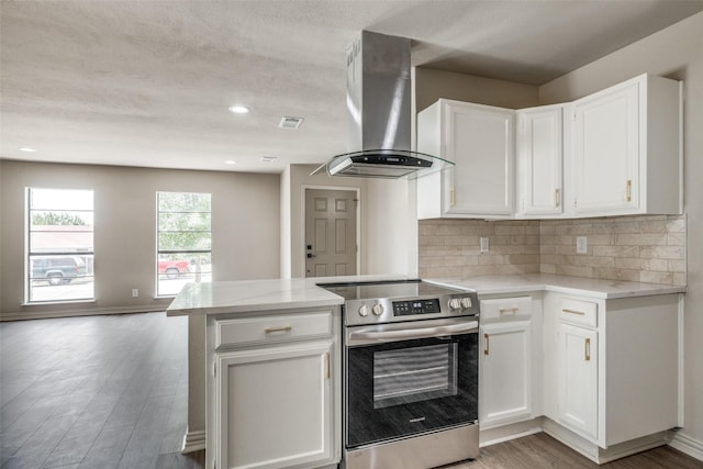 1336 Whittenburg Dr, Fort Worth, TX 76134 - kitchen featuring stainless steel range with electric cooktop, wall chimney range hood, a peninsula, and white cabinetry