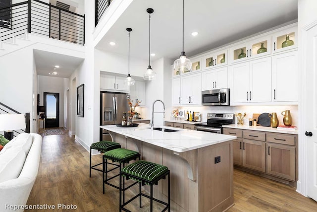 8409 Peach St, Justin, TX 76247 - kitchen featuring appliances with stainless steel finishes, a sink, dark wood-style floors, hanging light fixtures, and an island with sink