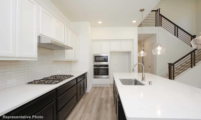 8409 Peach St, Justin, TX 76247 - kitchen with stainless steel appliances, a sink, under cabinet range hood, white cabinets, and recessed lighting
