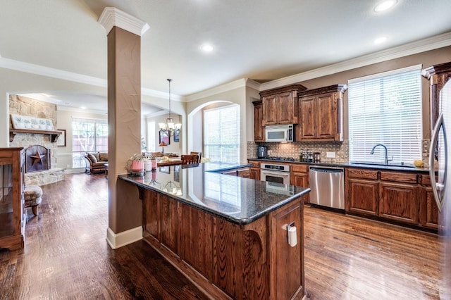 5946 Wallis Dr, Frisco, TX 75033 - kitchen with stainless steel appliances, dark wood finished floors, a sink, a stone fireplace, and dark stone countertops