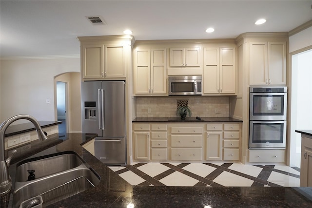 720 Madeline Ct, Azle, TX 76020 - kitchen featuring stainless steel appliances, a sink, arched walkways, cream cabinets, and inlaid floor details