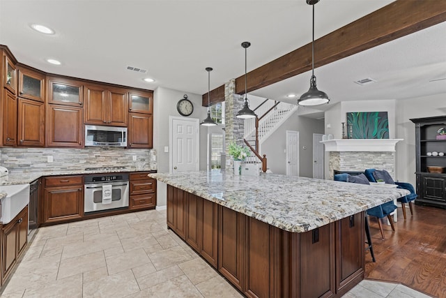 5655 Redgum Dr, Fort Worth, TX 76244 - kitchen with appliances with stainless steel finishes, decorative backsplash, light stone countertops, a spacious island, and glass insert cabinets