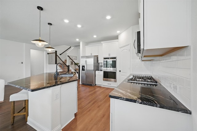 3501 Alamosa River Dr, Prosper, TX 75078 - kitchen with stainless steel appliances, a sink, light wood-style flooring, white cabinets, and decorative backsplash