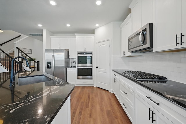 3501 Alamosa River Dr, Prosper, TX 75078 - kitchen featuring stainless steel appliances, a sink, wood finished floors, white cabinets, and recessed lighting