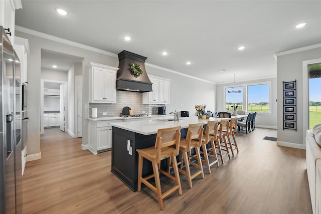 132 Parkview Ln, Boyd, TX 76023 - kitchen with premium range hood, an island with sink, white cabinetry, light wood-type flooring, and recessed lighting
