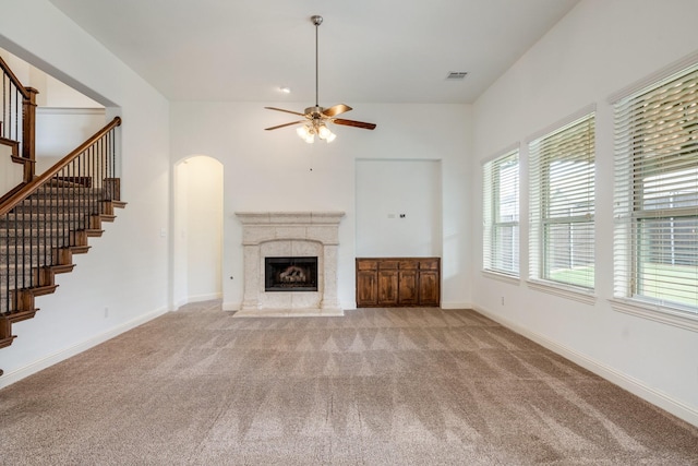 546 El Camino Dr, Frisco, TX 75036 - unfurnished living room featuring carpet floors, stairs, a ceiling fan, a high end fireplace, and arched walkways