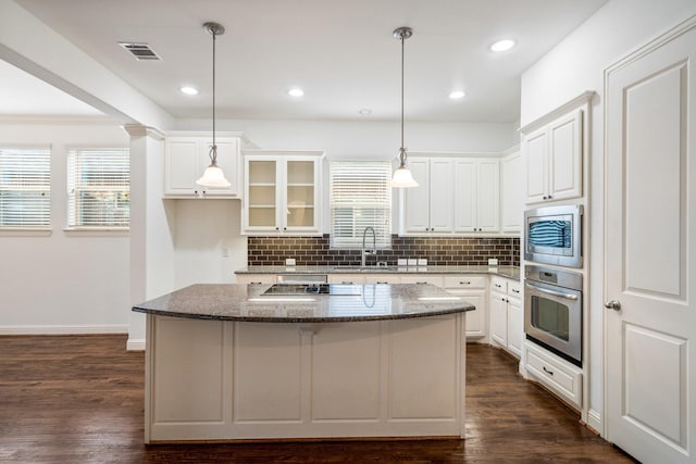546 El Camino Dr, Frisco, TX 75036 - kitchen with stainless steel appliances, decorative backsplash, a kitchen island, white cabinetry, and dark stone counters