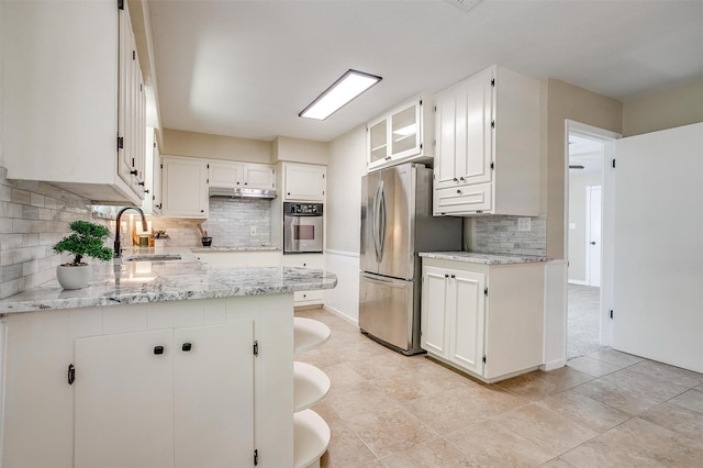 1309 Manor Dr, Cleburne, TX 76033 - kitchen with appliances with stainless steel finishes, backsplash, a sink, white cabinetry, and light stone counters