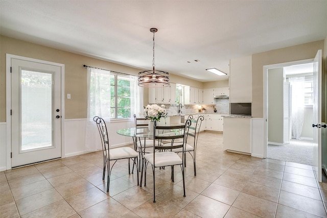 1309 Manor Dr, Cleburne, TX 76033 - dining area with light tile patterned floors, a wainscoted wall, and a chandelier