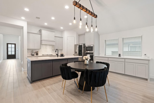 2316 Lazy Dog Ln, Northlake, TX 76247 - kitchen with appliances with stainless steel finishes, light countertops, a center island with sink, backsplash, and light wood finished floors