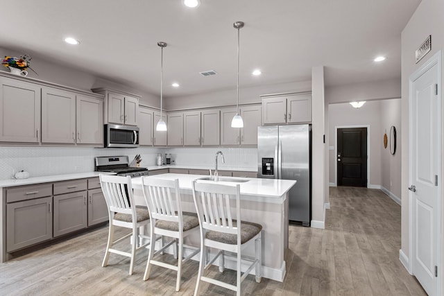 601 Big Horn Pass, Denton, TX 76210 - kitchen with stainless steel appliances, gray cabinetry, a sink, a kitchen island with sink, and light wood-style flooring