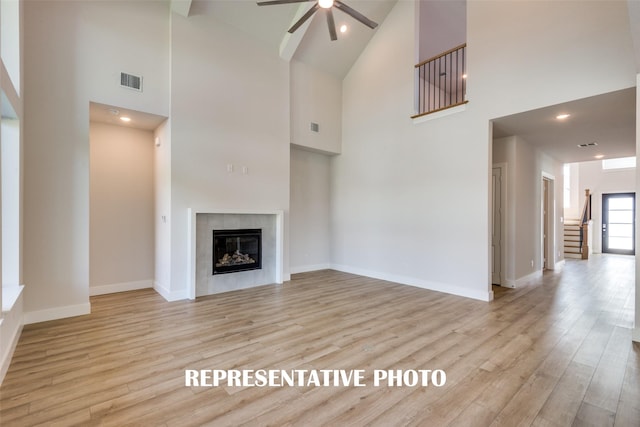 4221 Holland Ct, Prosper, TX 75078 - unfurnished living room with high vaulted ceiling, ceiling fan, a fireplace, light wood-style flooring, and stairs