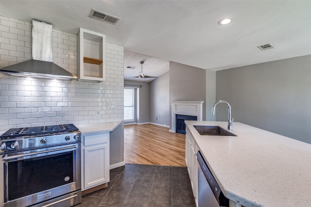 630 W Canty St Unit B6, Dallas, TX 75208 - kitchen featuring appliances with stainless steel finishes, wall chimney exhaust hood, a sink, a fireplace, and white cabinets