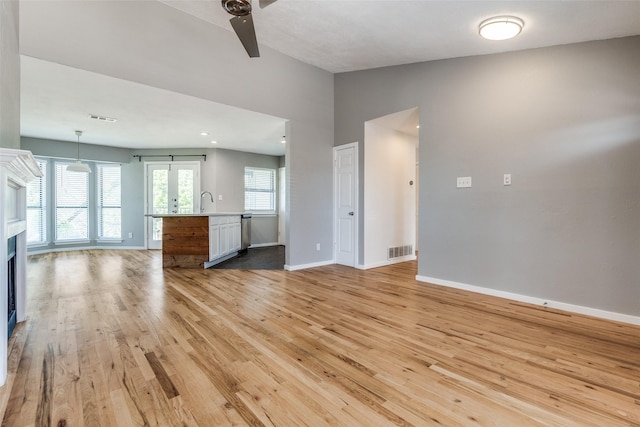 630 W Canty St Unit B6, Dallas, TX 75208 - unfurnished living room with vaulted ceiling, light wood-type flooring, baseboards, a ceiling fan, and a fireplace