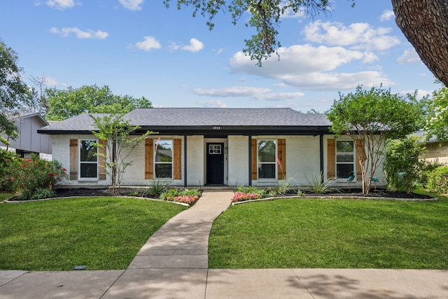 1833 Chamberlain Dr, Carrollton, TX 75007 - ranch-style home featuring brick siding, a front yard, roof with shingles, and covered porch